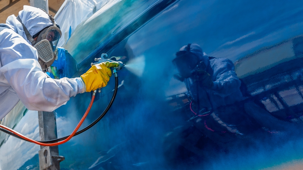 a person spraying a car with antifouling paint